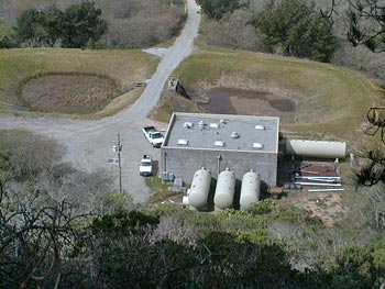 Concrete square building with three large water tanks behind it